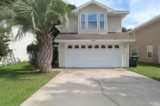 a front view of a house with a garden and trees