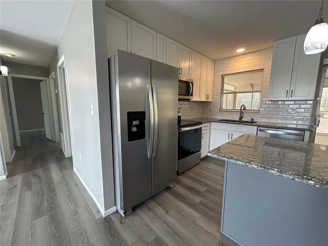 a kitchen with stainless steel appliances granite countertop a refrigerator a stove and a sink