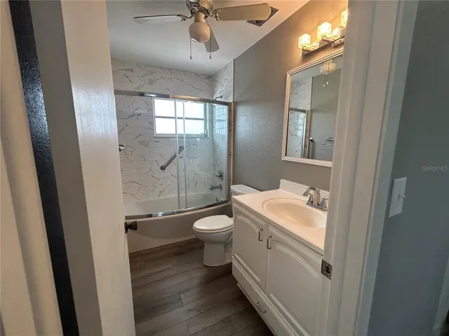a bathroom with a granite countertop toilet a sink and a mirror