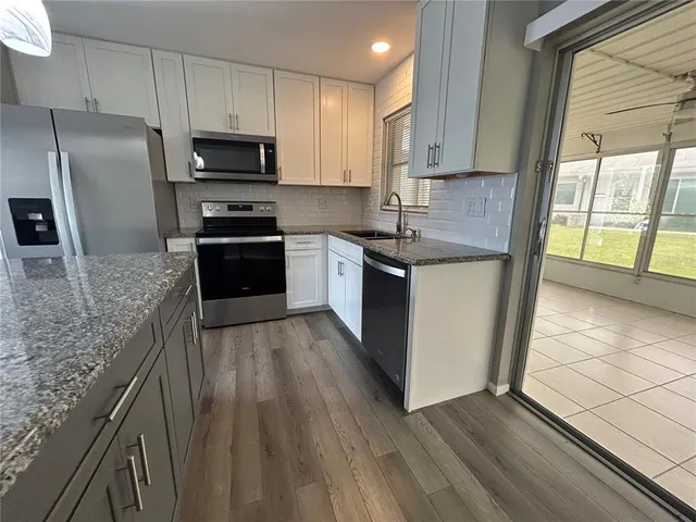 a kitchen with stainless steel appliances granite countertop a stove a sink and a refrigerator