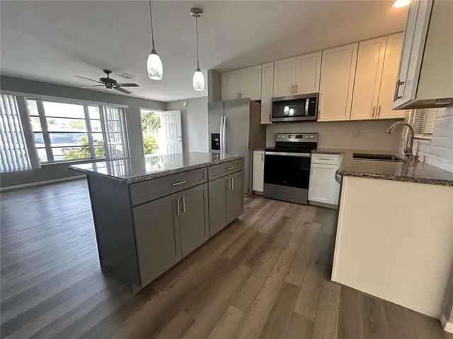 a large kitchen with stainless steel appliances granite countertop a stove a sink dishwasher and a microwave oven with wooden floor