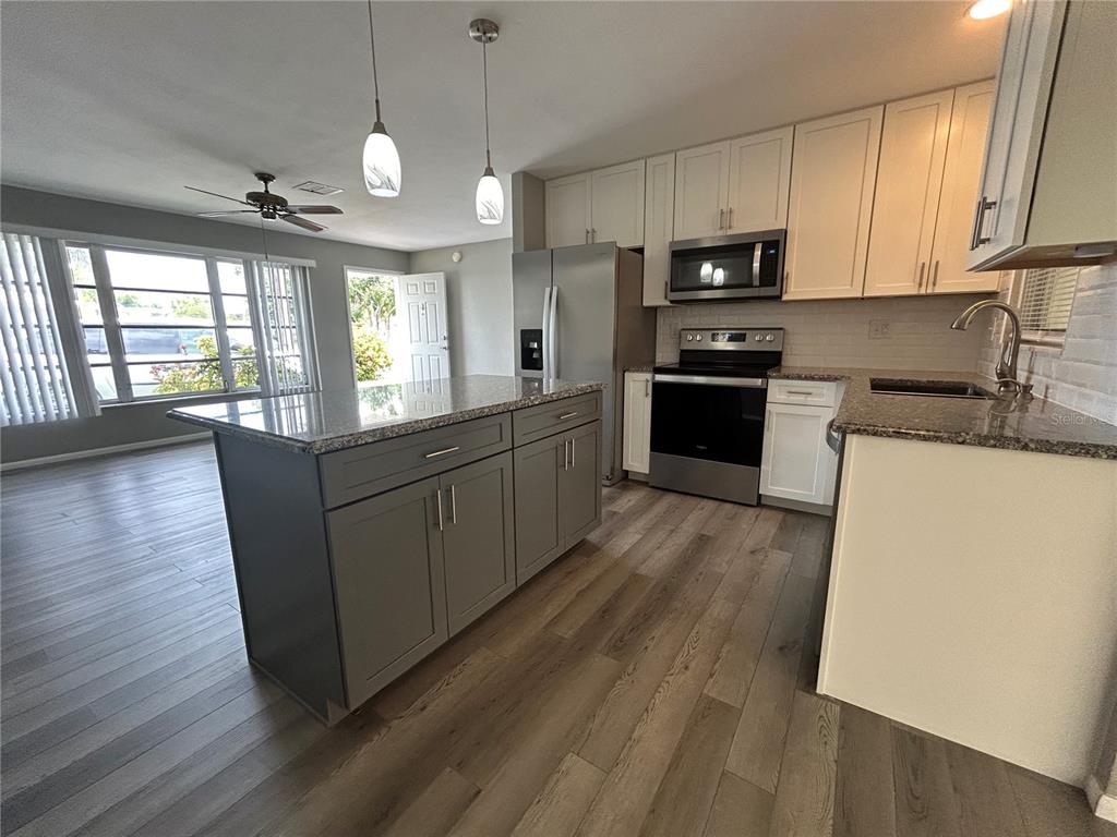 8521 Pickwick Road North Port, FL 34287 - Photo 6 of 19 a large kitchen with stainless steel appliances granite countertop a stove a sink dishwasher and a microwave oven with wooden floor