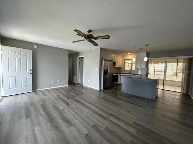 a view of a big room with wooden floor and a kitchen