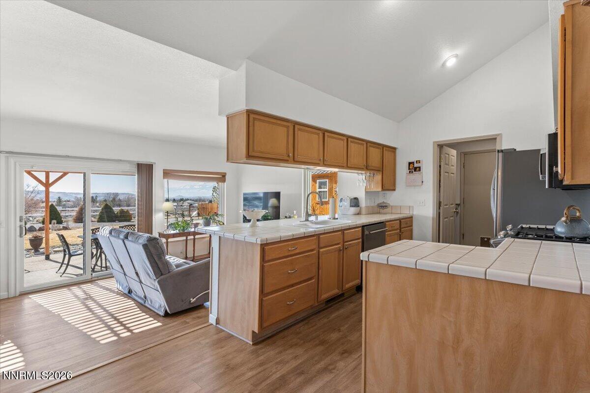 9580 Benedict Drive Sparks, NV 89441 - Photo 11 of 40 a kitchen with stainless steel appliances a stove a sink a refrigerator white cabinets and wooden floor