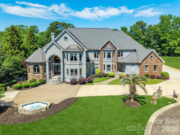a view of a house with a big yard plants and large trees