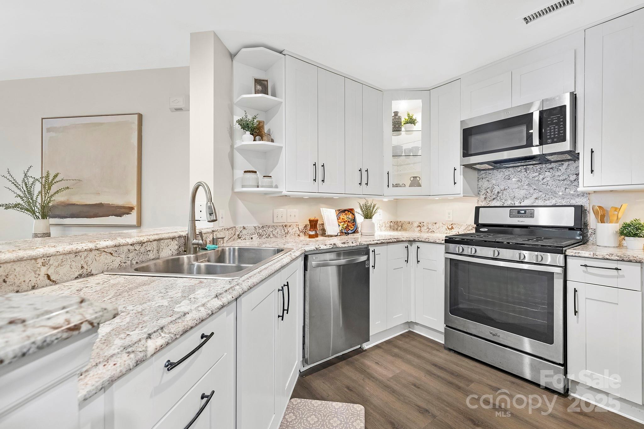 17811 Half Moon Lane, Unit E Cornelius, NC 28031 - Photo 11 of 42 a kitchen with granite countertop a sink stainless steel appliances and white cabinets