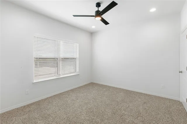 en empty room with a ceiling fan and window