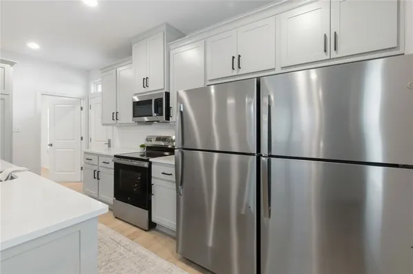 a kitchen with stainless steel appliances a refrigerator a stove a dining table and chairs