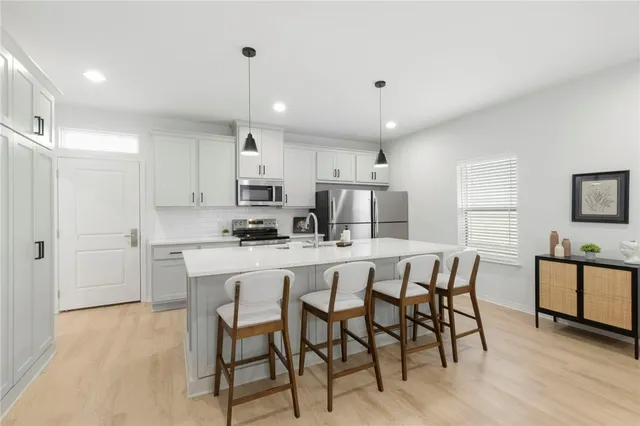a kitchen with stainless steel appliances granite countertop a kitchen island a stove a table and chairs