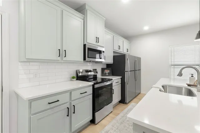 a large white kitchen with a sink and dishwasher with white cabinets