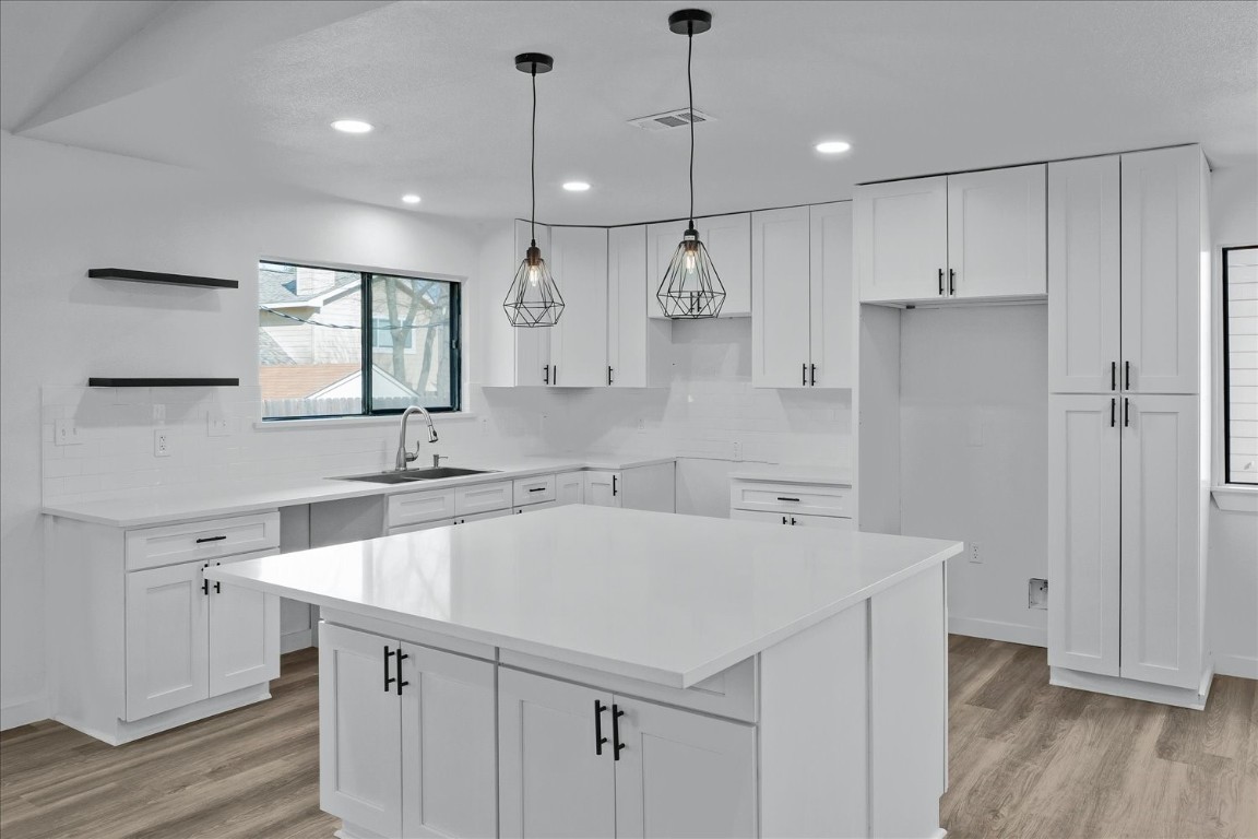 a kitchen with a sink a center island cabinets and a window