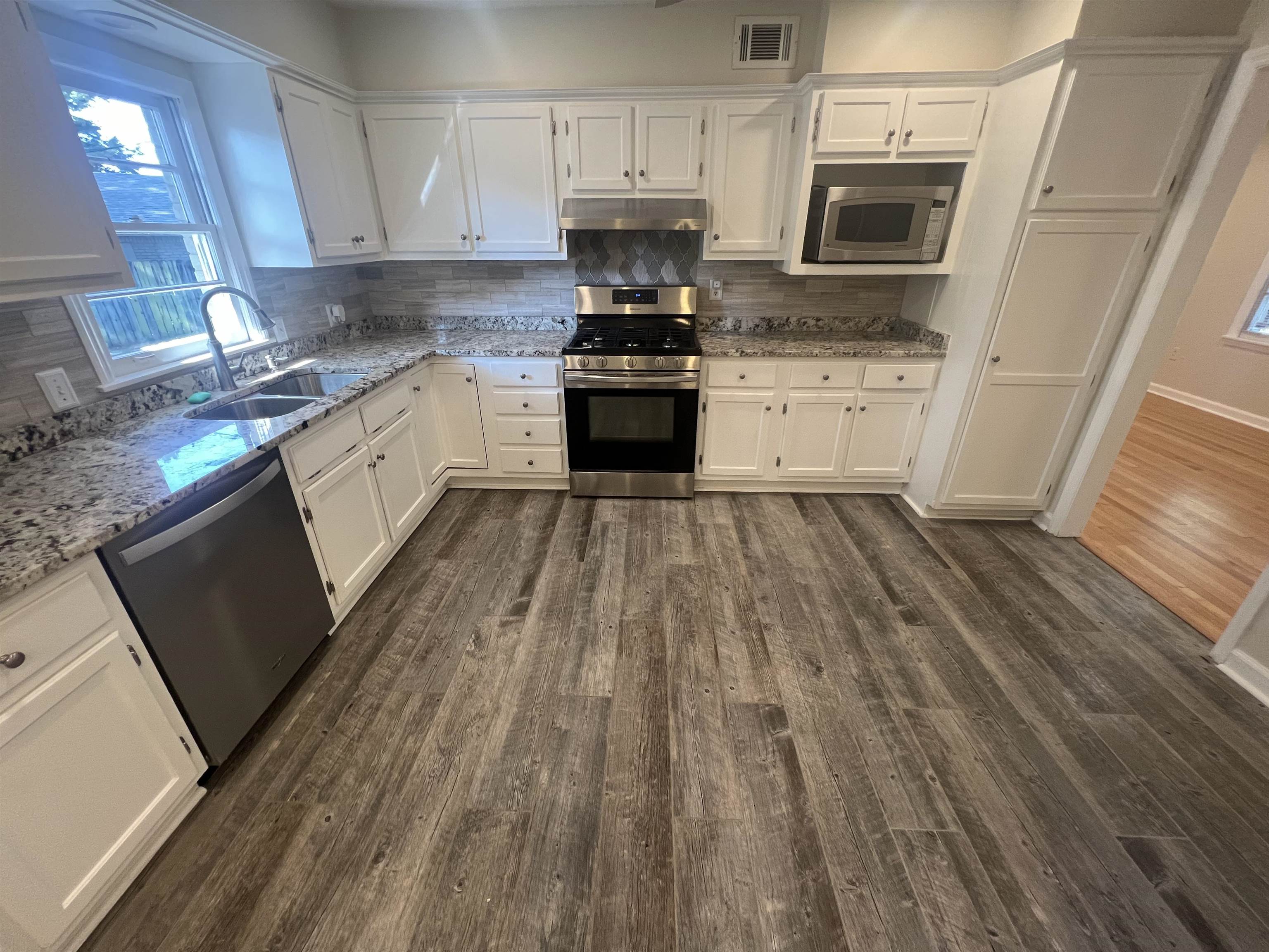 5131 Verne Road Memphis, TN 38117 - Photo 6 of 35 Kitchen with white cabinetry, tasteful backsplash, light stone counters, dark hardwood / wood-style floors, and appliances with stainless steel finishes