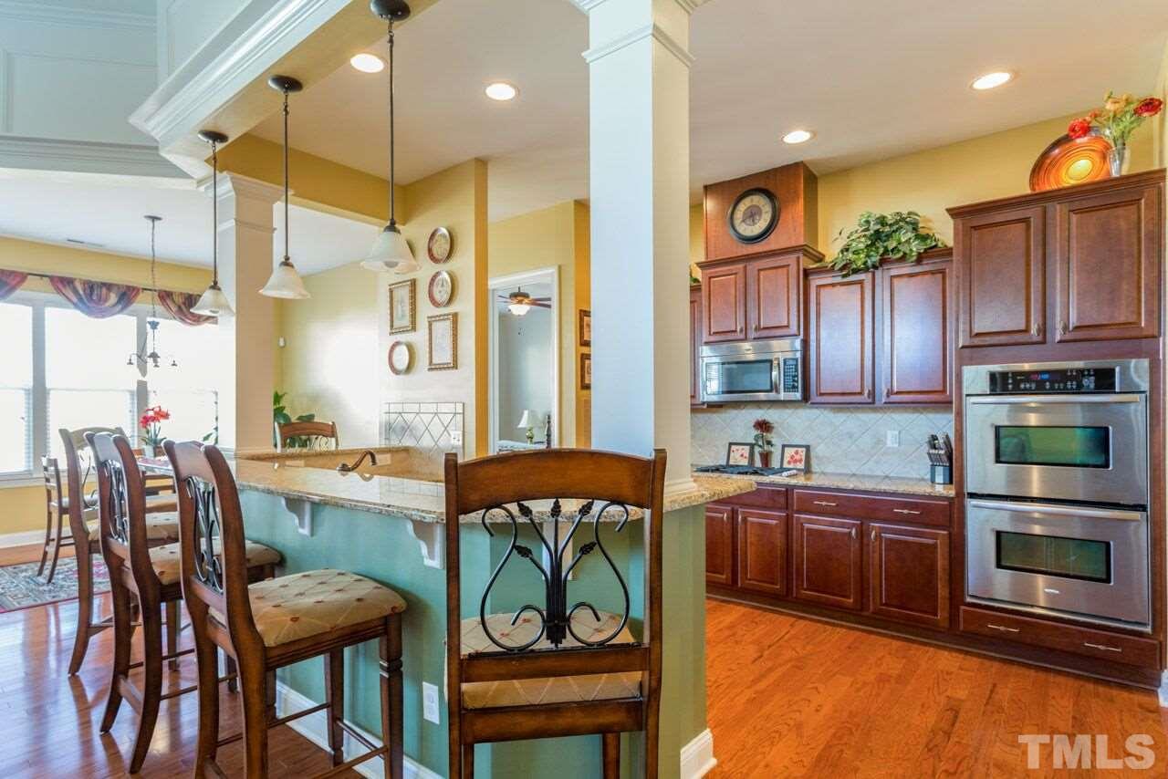 1217 Chapanoke Road Raleigh, NC 27603 - Photo 17 of 25 a kitchen with stainless steel appliances a table chairs and a refrigerator