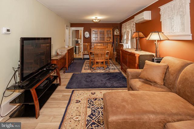 a living room with furniture a flat screen tv and a refrigerator