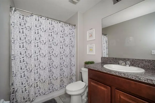 a bathroom with a granite countertop sink toilet and a mirror