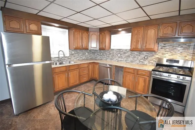 a kitchen with stainless steel appliances granite countertop a stove a sink dishwasher a refrigerator and a microwave
