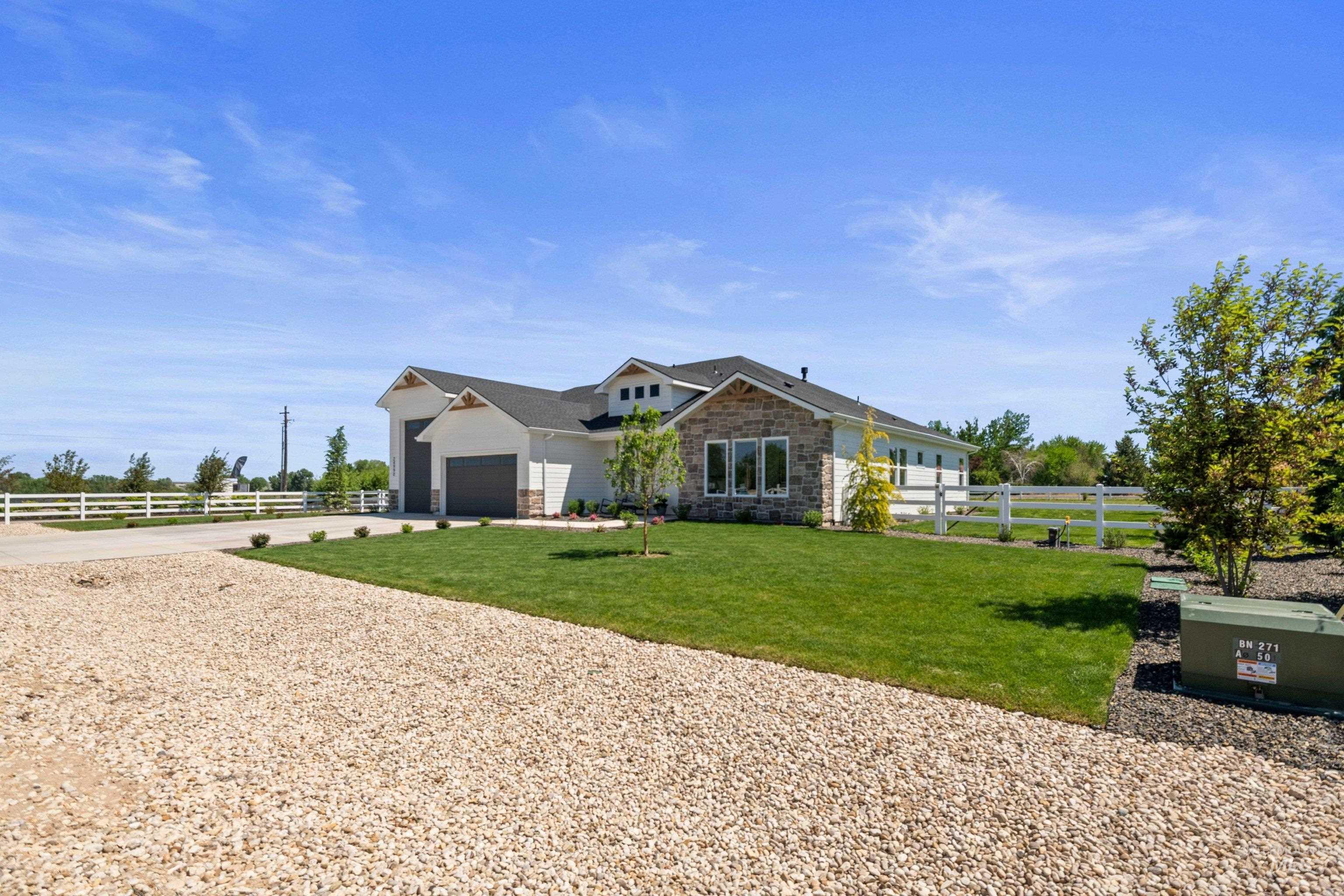 24990 Belgian Way Middleton, ID 83644 - Photo 5 of 50 Contemporary home exterior featuring white siding, stone accents, and dark gray garage doors