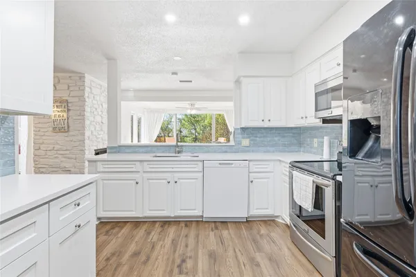 a kitchen with stainless steel appliances granite countertop a stove a sink and white cabinets