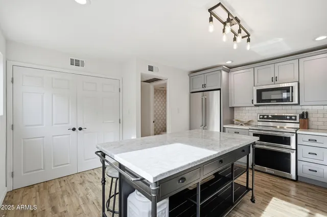 a kitchen with kitchen island a stove refrigerator and microwave
