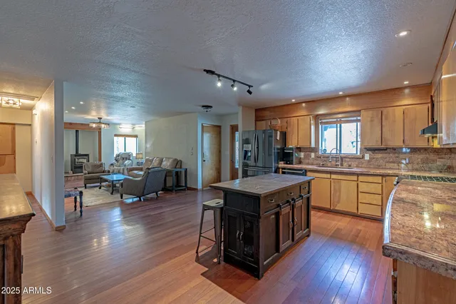 a kitchen with stainless steel appliances granite countertop a refrigerator a sink dishwasher a stove and white countertops with wooden floor