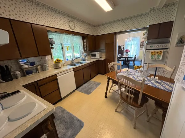a kitchen with stainless steel appliances kitchen island granite countertop a table chairs and a refrigerator