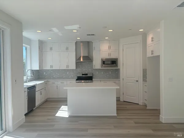 a large kitchen with stainless steel appliances a large counter top a stove and a refrigerator