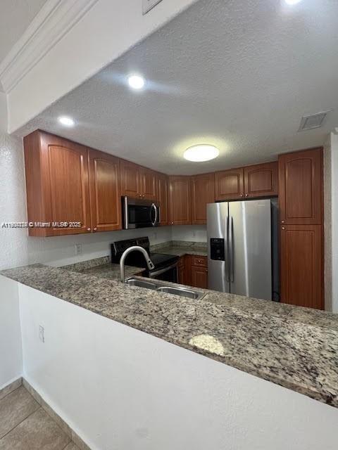 7250 Northwest 174th Terrace, Unit 102 Hialeah, FL 33015 - Photo 12 of 37 a kitchen with stainless steel appliances granite countertop a refrigerator a stove and a sink with wooden cabinets