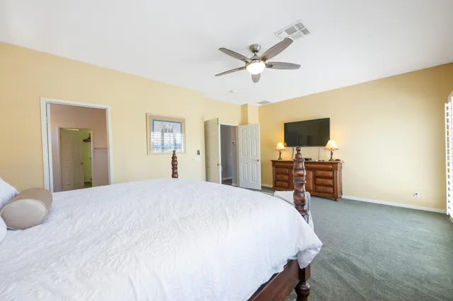 a spacious bedroom with a bed and a flat screen tv