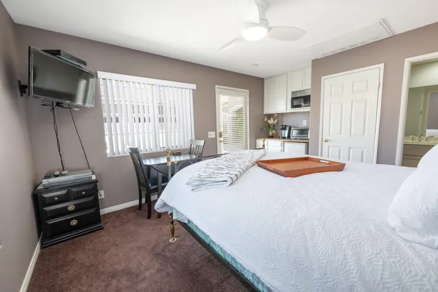 a spacious bedroom with a bed a desk and flat screen tv