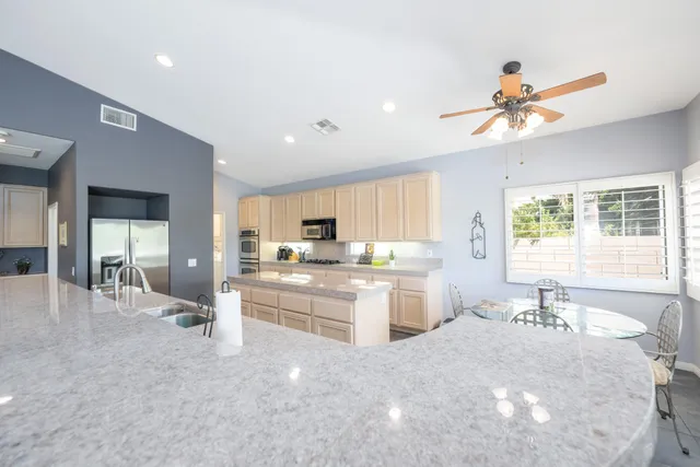 a large white kitchen with a large window a sink and a stove top oven