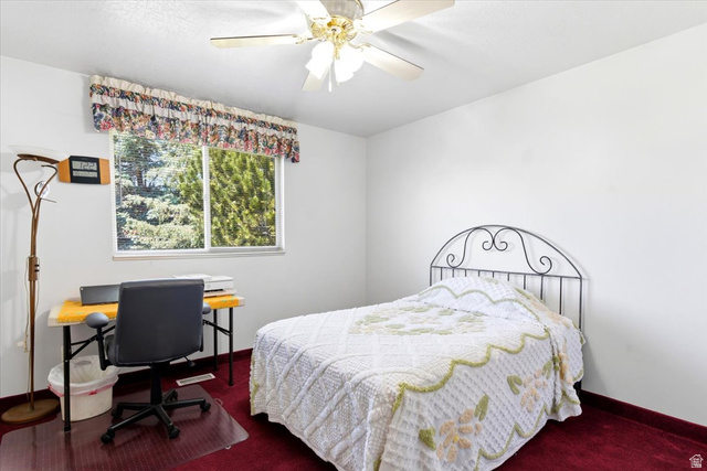 72 Canal Bank Road Garland, UT 84312 - Photo 17 of 40 Bedroom featuring a window with a valance, a ceiling fan, and red carpeting