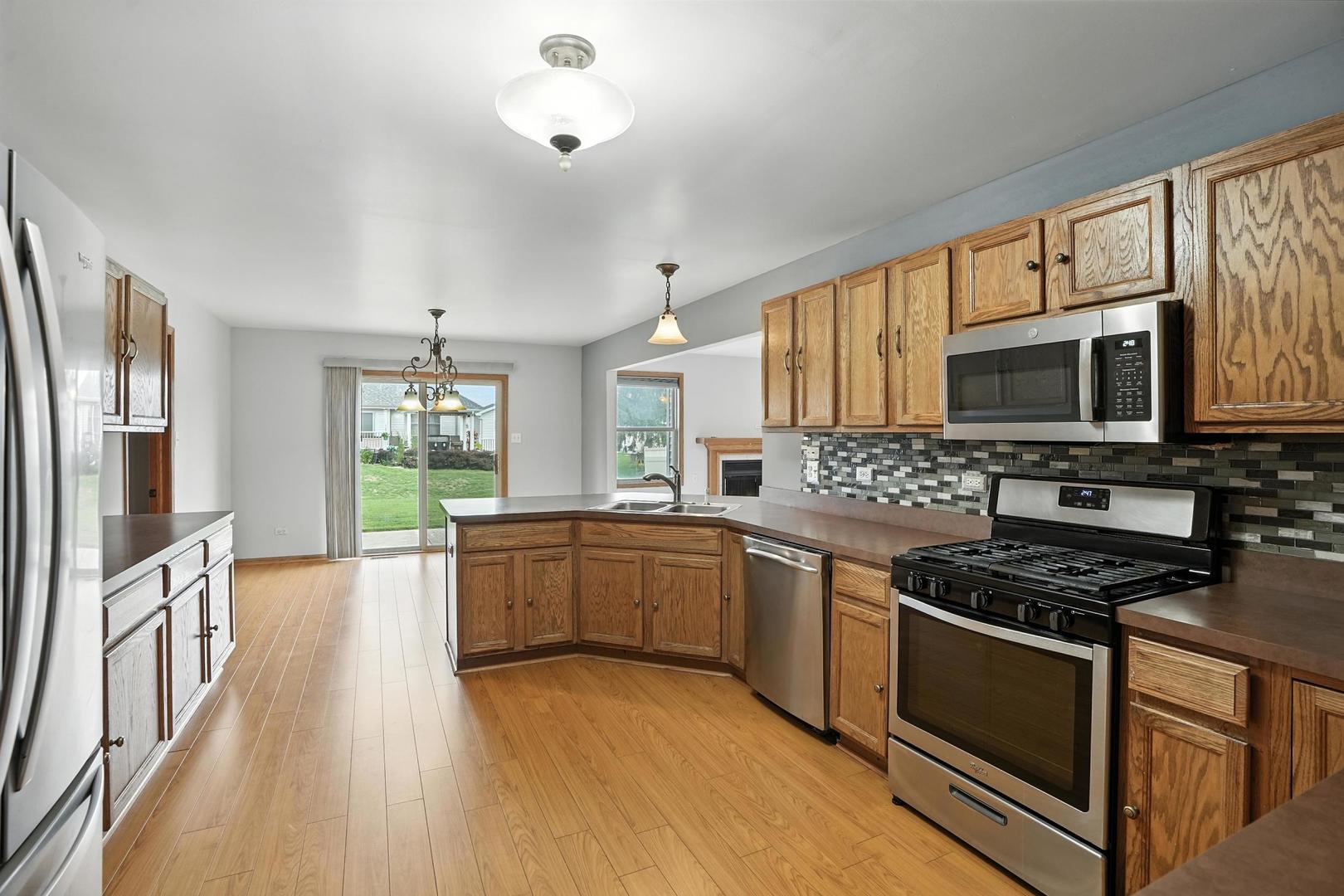 1665 Fox Hound Trail Beecher, IL 60401 - Photo 3 of 34 a kitchen with stainless steel appliances granite countertop a stove top oven a sink dishwasher a refrigerator and cabinets with wooden floor