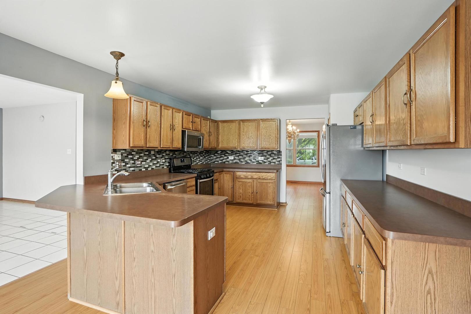 1665 Fox Hound Trail Beecher, IL 60401 - Photo 5 of 34 a kitchen with granite countertop a sink a counter top space stainless steel appliances and cabinets