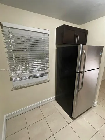 a view of a refrigerator in kitchen and an empty room