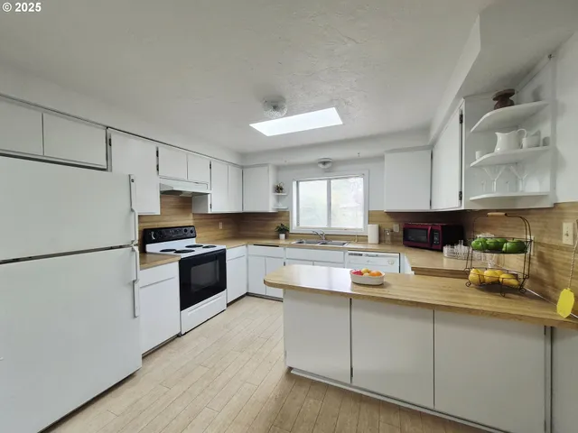 a kitchen with stainless steel appliances a refrigerator sink and white cabinets