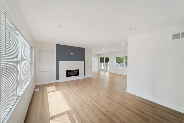 a view of a livingroom with wooden floor and a fireplace