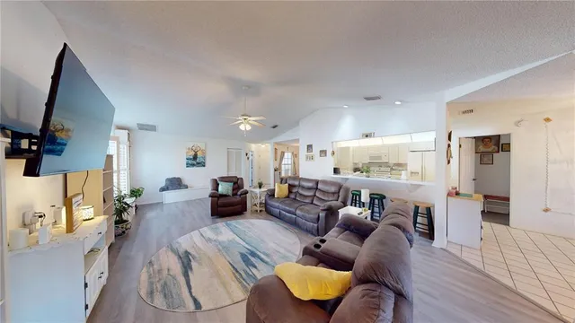 a living room with furniture kitchen view and a wooden floor