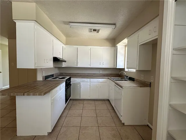 a kitchen with stainless steel appliances granite countertop a sink and dishwasher a stove top oven with white cabinets