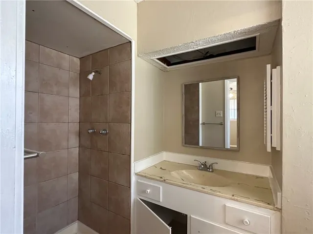a bathroom with a granite countertop sink a mirror and shower