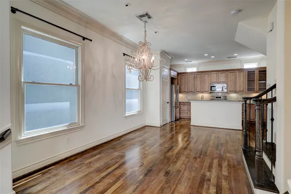 a kitchen with stainless steel appliances granite countertop a refrigerator a sink dishwasher a stove and white countertops with wooden floor