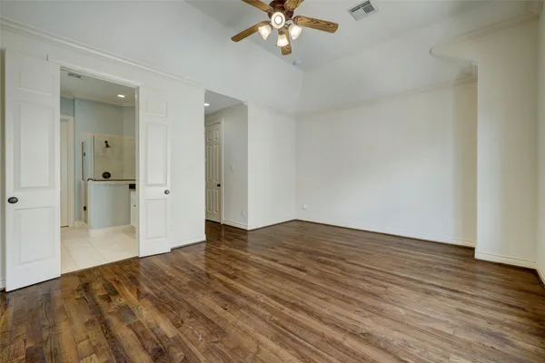 wooden floor in an empty room with a chandelier fan