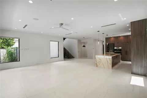 a large white room with kitchen view and a refrigerator