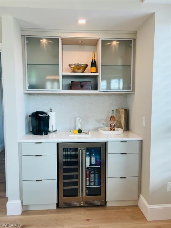 9115 Strada Place, Unit 5502 Naples, FL 34108 - Photo 12 of 48 Indoor dry bar with modern cabinets, wine cooler, and light wood-style flooring
