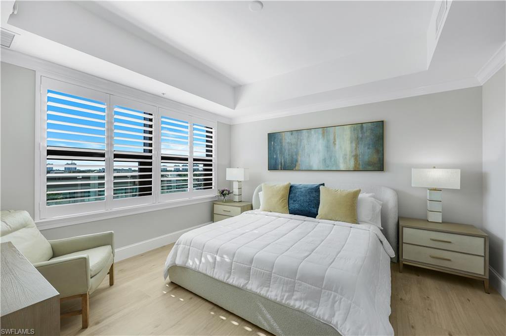 9115 Strada Place, Unit 5502 Naples, FL 34108 - Photo 18 of 48 Primary Bedroom with a tray ceiling , plantation shutters and wood finished floors