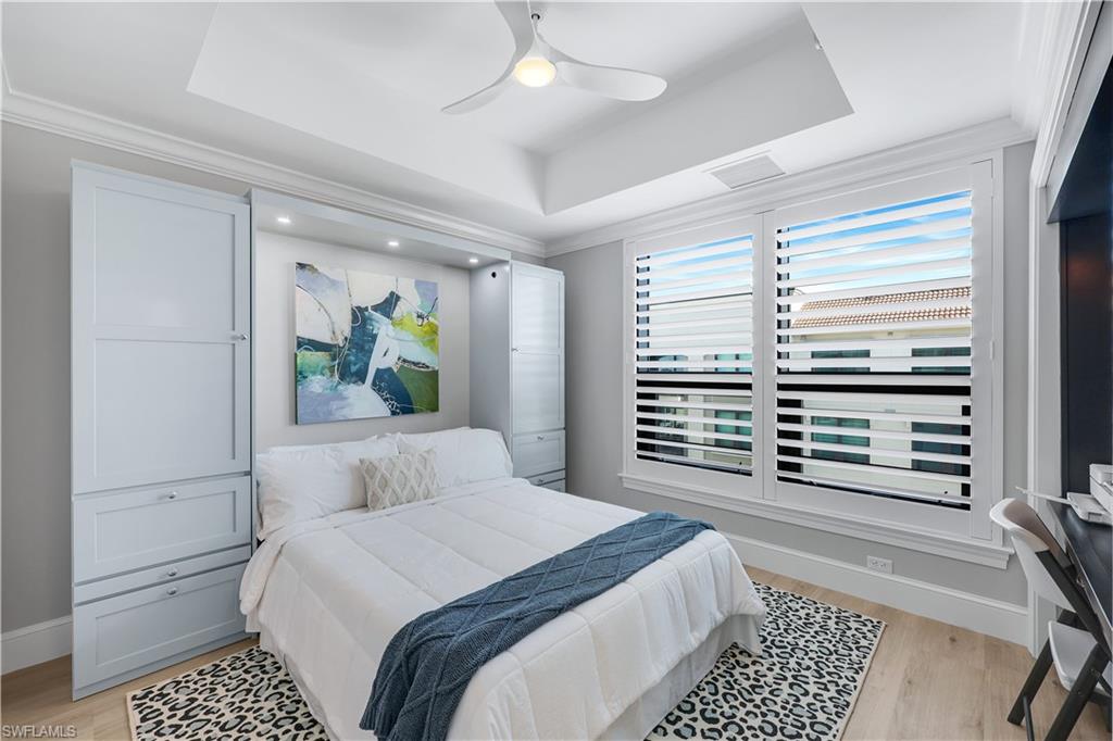 9115 Strada Place, Unit 5502 Naples, FL 34108 - Photo 22 of 48 Second Bedroom featuring a raised ceiling, ceiling fan, light wood-style flooring and plantation shutters