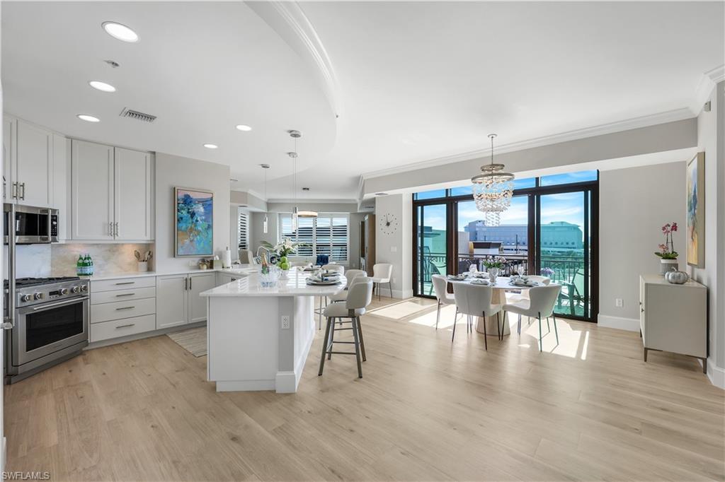 9115 Strada Place, Unit 5502 Naples, FL 34108 - Photo 3 of 48 Kitchen featuring white cabinets, a kitchen bar, decorative light fixtures, tasteful backsplash, and appliances with stainless steel finishes