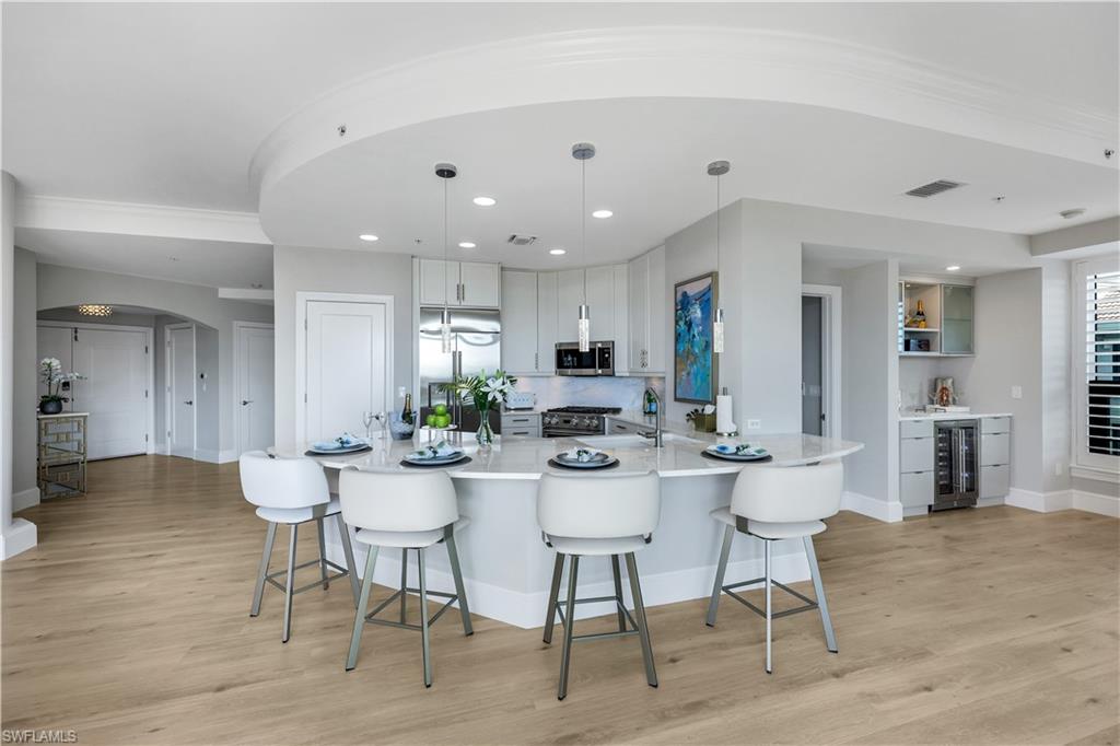 9115 Strada Place, Unit 5502 Naples, FL 34108 - Photo 4 of 48 Kitchen featuring arched walkways, high end appliances, a kitchen bar, a peninsula, and hanging light fixtures