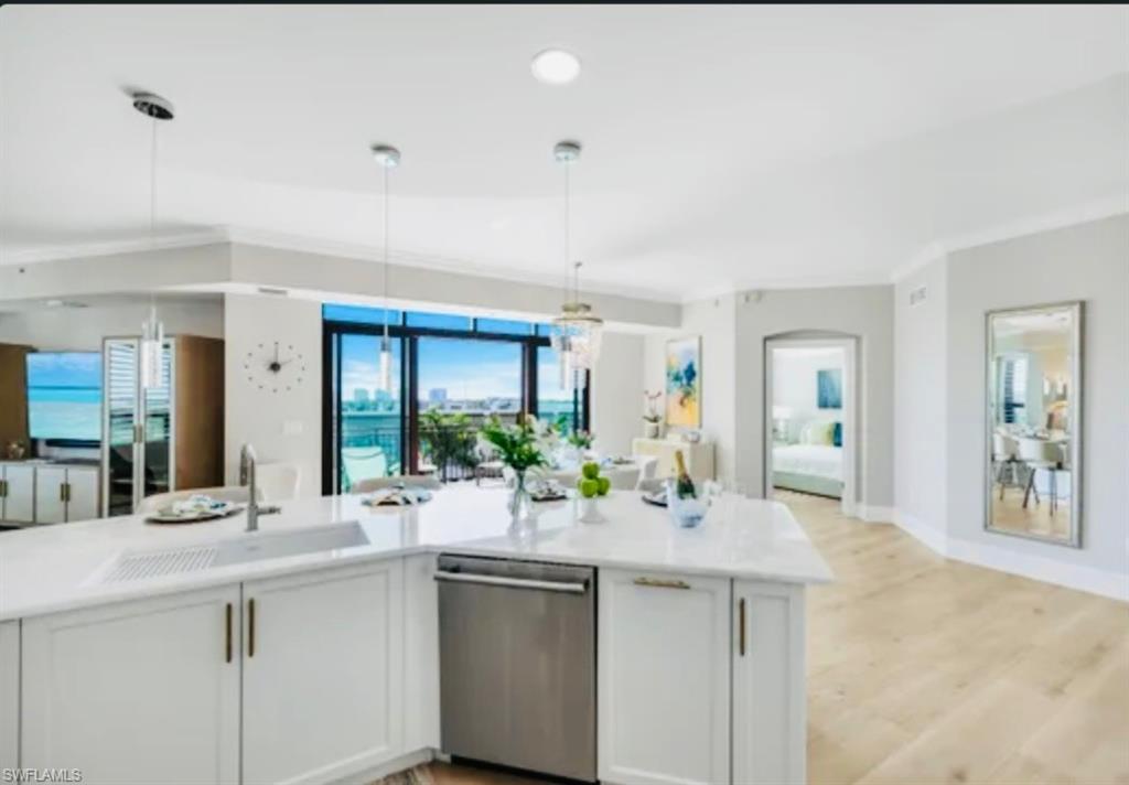 9115 Strada Place, Unit 5502 Naples, FL 34108 - Photo 10 of 48 Open Majestic Kitchen featuring white cabinets, stainless steel dishwasher, hanging light fixtures, and light wood-style flooring