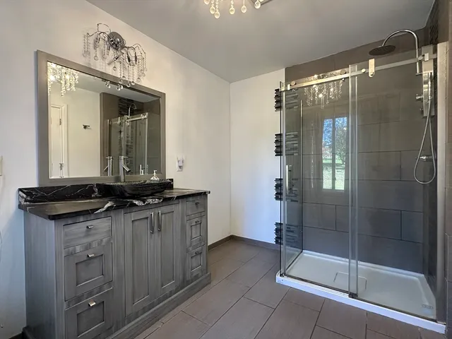 a bathroom with a granite countertop sink a mirror and a shower