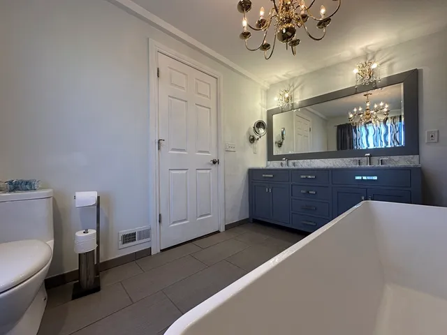 a spacious bathroom with a toilet a sink and mirror